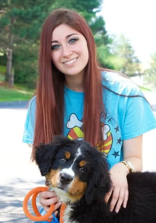 A woman with long red hair and a black dog.