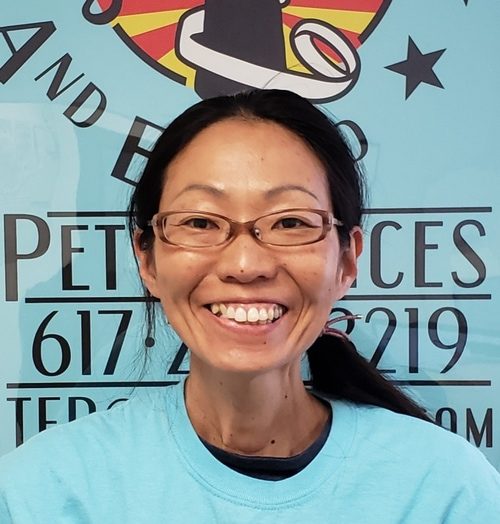 A woman with glasses standing in front of a blue sign.