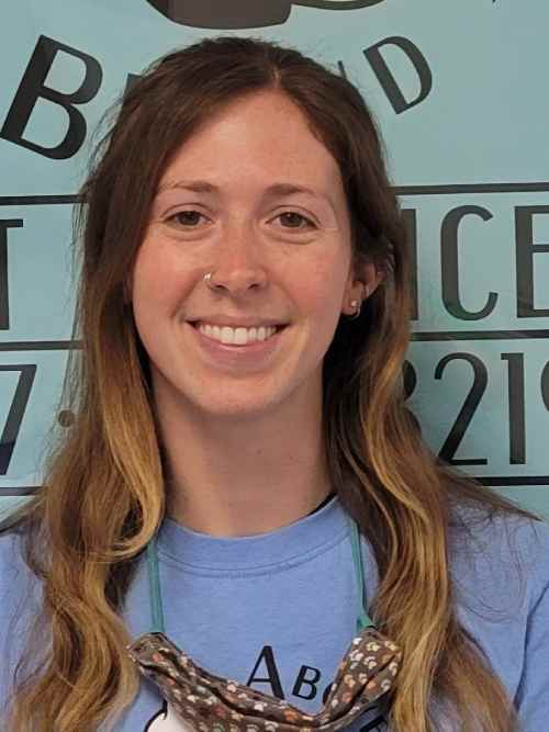 A woman with long hair and blue shirt smiling.