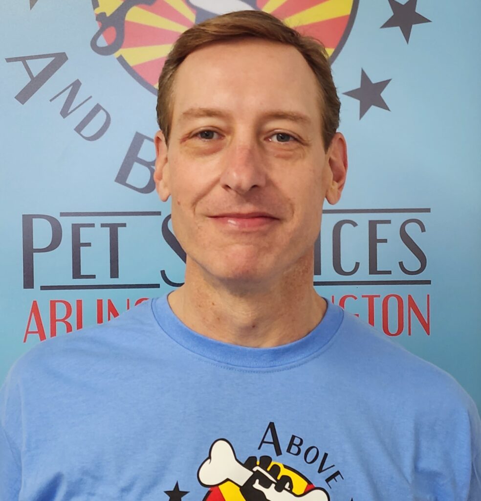 A man in blue shirt standing next to a wall.