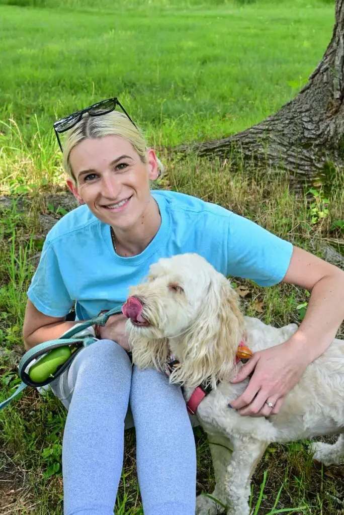 A woman sitting on the ground with her dog.