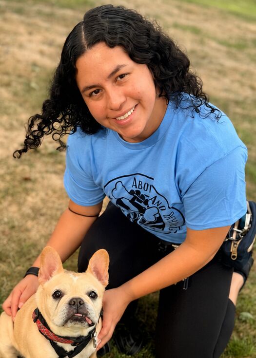 Woman kneeling next to a French bulldog.