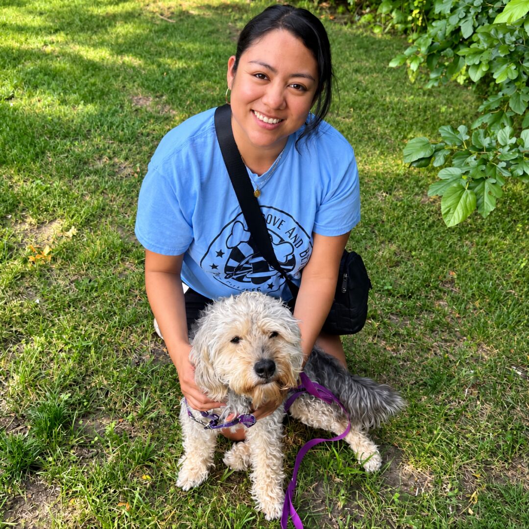 Woman kneeling with her dog in the grass.