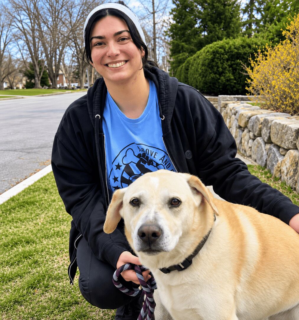 Smiling woman with a yellow dog outdoors.