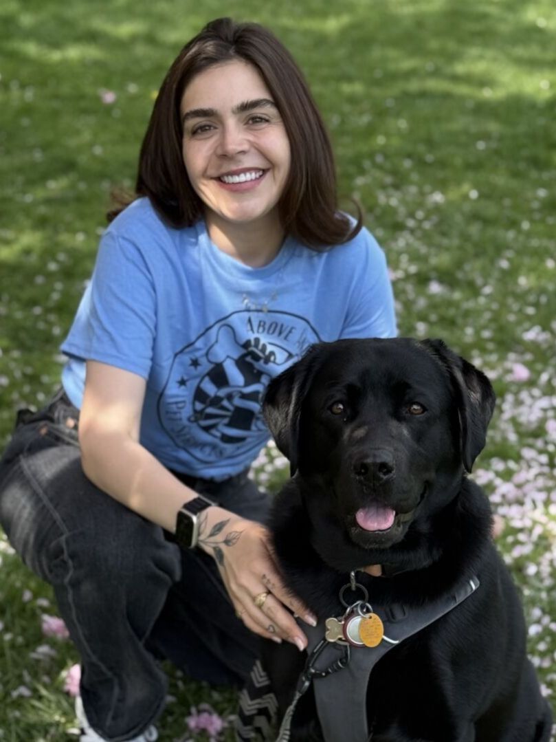 Smiling person with black dog in park