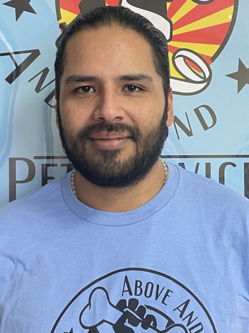 Man with beard and mustache smiling, wearing a light blue shirt.