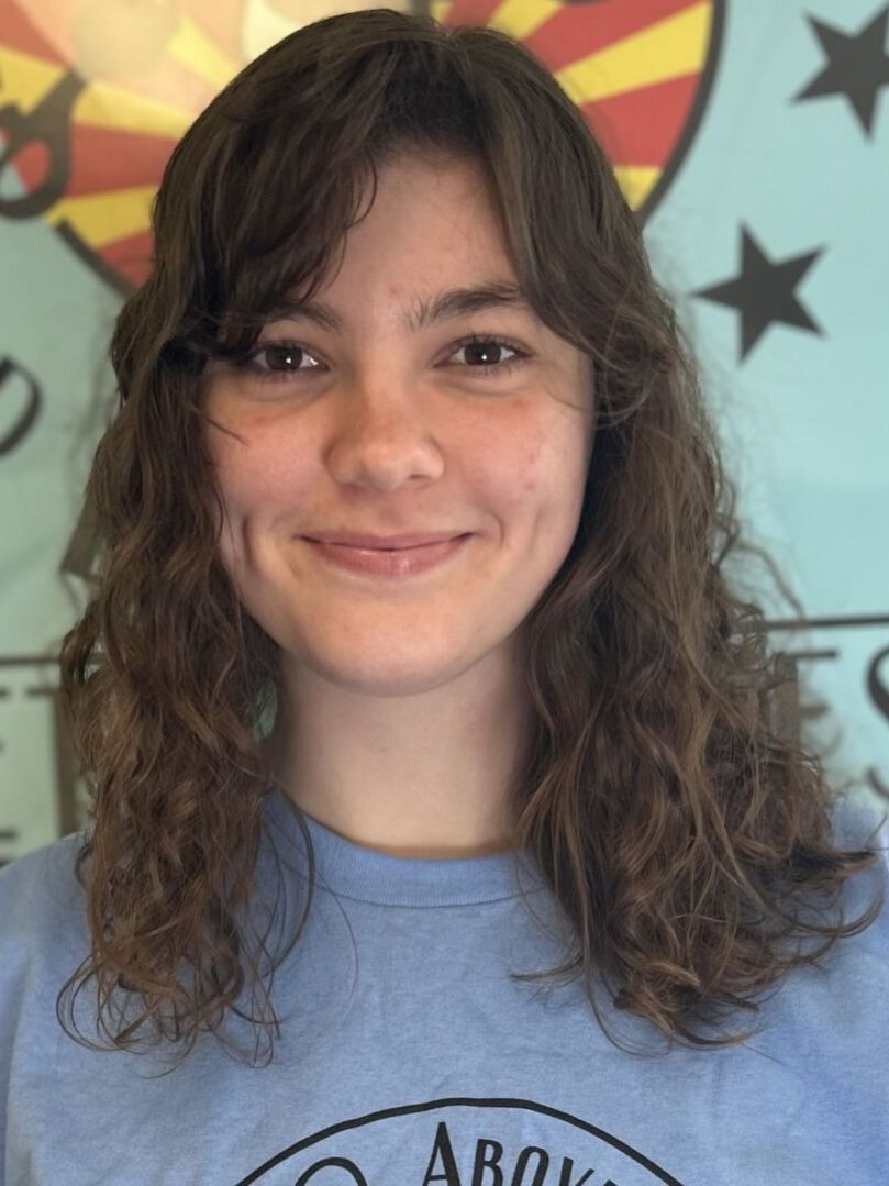 Smiling person with wavy hair and blue shirt